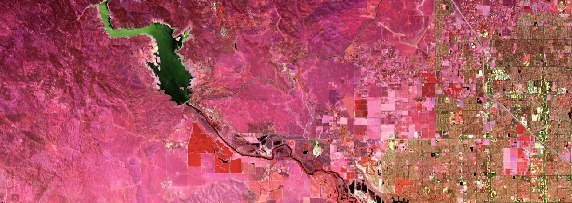 A hyperspectral satellite photo of an area in California, USA, showing a landscape, a lake, and human dwellings.